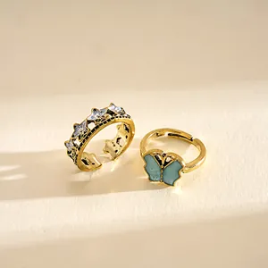 Detail view of vintage gold rings with butterfly and star motifs in warm sunlight.