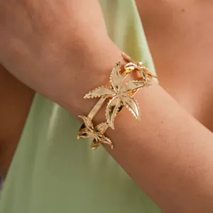 Detail view of an elegant gold-plated starfish cuff bracelet on a model's wrist