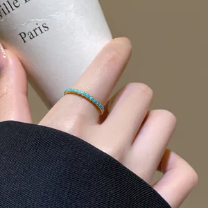 Nahaufnahme eines vergoldeten 18 Karat offenen Rings mit kleinen türkisfarbenen Steinen