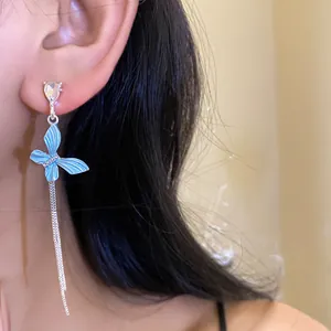 Primo piano di un orecchino a nappa a farfalla blu con strass scintillanti sul modello.