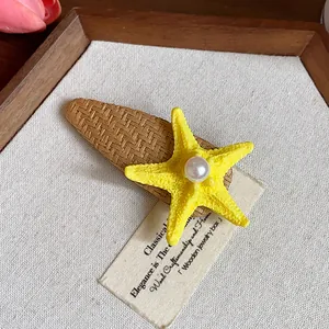 Detailed close-up of a bohemian yellow starfish hair clip with a central pearl embellishment