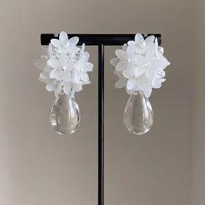 Detailed view of elegant white floral cluster earrings with clear teardrop pendants.
