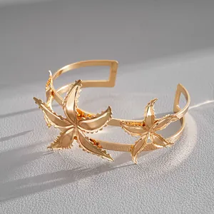 Close-up detail of a gold starfish-shaped metal cuff bracelet on a textured gray background