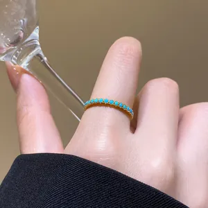 Nahaufnahme eines 18 Karat vergoldeten Rings mit türkisfarbenen Steinen am Finger.