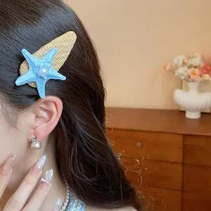 Detail view of a Bohemian blue starfish hair clip with pearl worn on wavy dark hair
