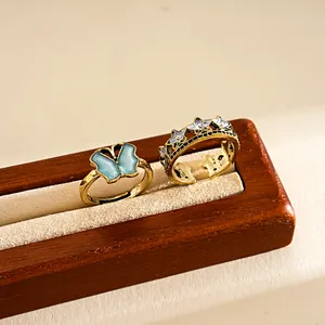 Detailed view of two vintage-style butterfly and star open rings on a wooden stand.