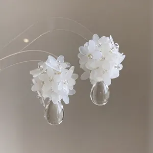 Close-up of elegant white flower cluster earrings with clear waterdrop pendants