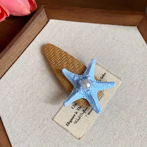 Close-up of a bohemian starfish hair clip featuring a pearl on a brown woven base