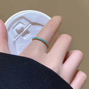 Detailaufnahme eines zarten 18 Karat vergoldeten Rings mit kleinen türkisen Steinen