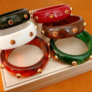 Vista dettagliata di bracciali rigidi retrò in resina colorata con borchie dorate moda