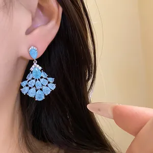 Gros plan de boucles d'oreilles vintage avec des gouttes de zircon bleu clair portées à l'oreille
