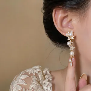 Vista dettagliata di eleganti orecchini pendenti placcati oro con perle e zirconi.