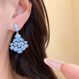 Gros plan d'élégantes boucles d'oreilles pendantes en zircon bleu clair portées à l'oreille