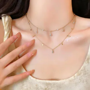 Primo piano di elegante collana dorata a due strati con ciondoli a goccia in zircone sul collo