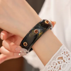 Primo piano di un bracciale in resina vintage con motivo dorato e borchie
