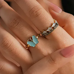Detailed macro shot of vintage butterfly and star crown ring set on finger, gold finish