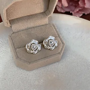Close-up of French style camellia flower stud earrings with heart crystal and pearl details