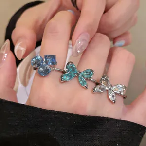 Vista detallada de anillos abiertos de circonita con diseño de mariposa y flores.