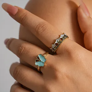 Close-up of vintage butterfly and star crown ring set on fingers with gold finish.