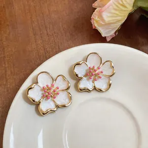 Close-up detail of elegant white enamel flower stud earrings with pink stamens