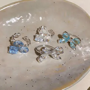 Detalle exquisito de anillos de mariposa de circonita de nicho francés en plato cerámico.