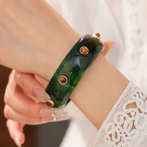 Vista dettagliata di un bracciale in resina marmorizzata verde con dettagli in rivetti dorati