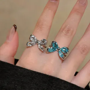 Vista macro de elegantes anillos de mariposa de circón azul y blanco en los dedos