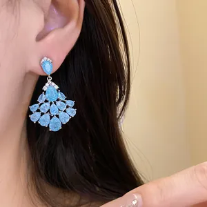 Gros plan d'élégantes boucles d'oreilles en zircon bleu portées par un mannequin.
