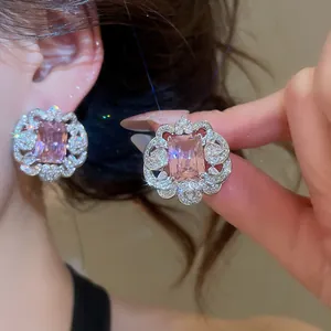 Close-up of elegant pink zircon earrings with ornate silver-tone floral borders.