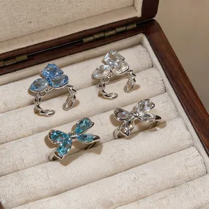 Detalle de anillos abiertos de mariposa de circón estilo francés en un joyero elegante.