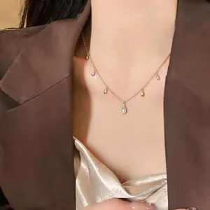 Dettaglio di una collana dorata con ciondoli a goccia di zircone indossata da una modella