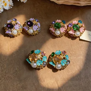 Macro view of vintage court-style stud earrings with pearl and enamel flower designs