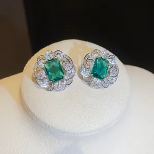 Close-up of luxury square emerald green zirconia earrings with intricate silver lace border.