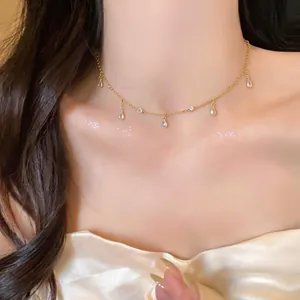 Primo piano di un'elegante collana con ciondolo a goccia in zircone dorato sulla modella