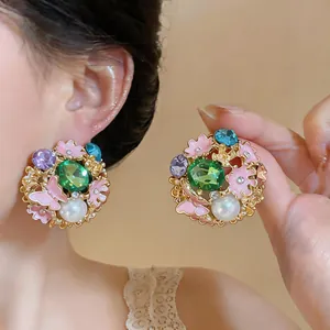 Detail of vintage enamel earrings with pearl, green crystal and pink flowers