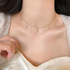 Elegante primo piano di una collana girocollo dorata con delicati ciondoli a goccia in zircone