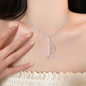 Close-up of elegant crystal beaded necklace with teardrop pendant on model collarbone.