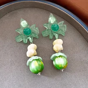 Detailed view of green resin flower earrings featuring white beads and green marbled pendants