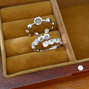 Detailed view of silver-tone open rings with sparkling zircons in a velvet box.