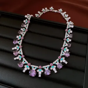Close-up of a vintage purple zircon necklace with enamel detailing on a black tray.