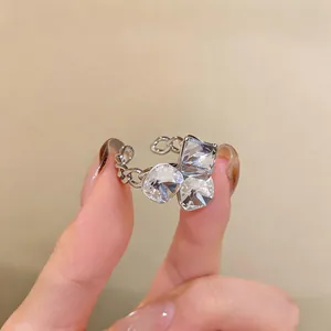 Primer plano de anillo ajustable estilo francés con tres circonitas claras y cadena.