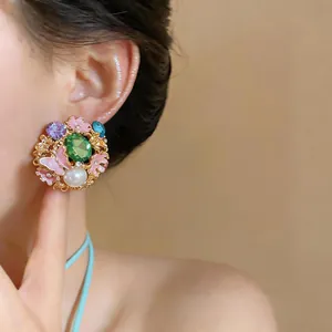 Detailed view of a vintage gold earring featuring a green gem, pearl, and pink butterflies.