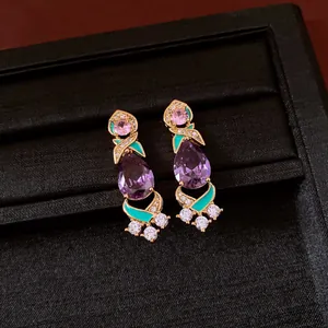Macro detail of vintage gold-plated earrings with purple pear zircon and teal enamel.