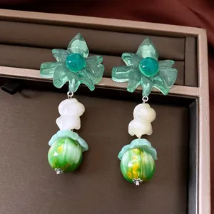 Detailed view of elegant green flower pendant earrings for beach vacation style.