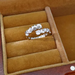 Macro detail of a silver-toned open ring with sparkling zircon and white resin beads.