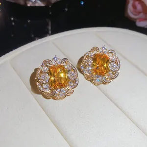 Close-up view of square yellow zircon stud earrings with sparkling flower border details