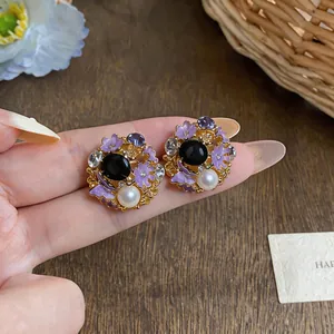 Close-up of vintage palace style earrings featuring purple enamel flowers and pearls