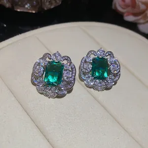 Close-up of luxury emerald-cut green cubic zirconia stud earrings with ornate floral halo