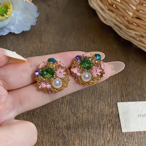 Close-up of vintage earrings with green gemstones, pink enamel flowers and pearls