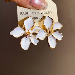 Elegant white enamel flower stud earrings with golden accents and hypoallergenic silver needles